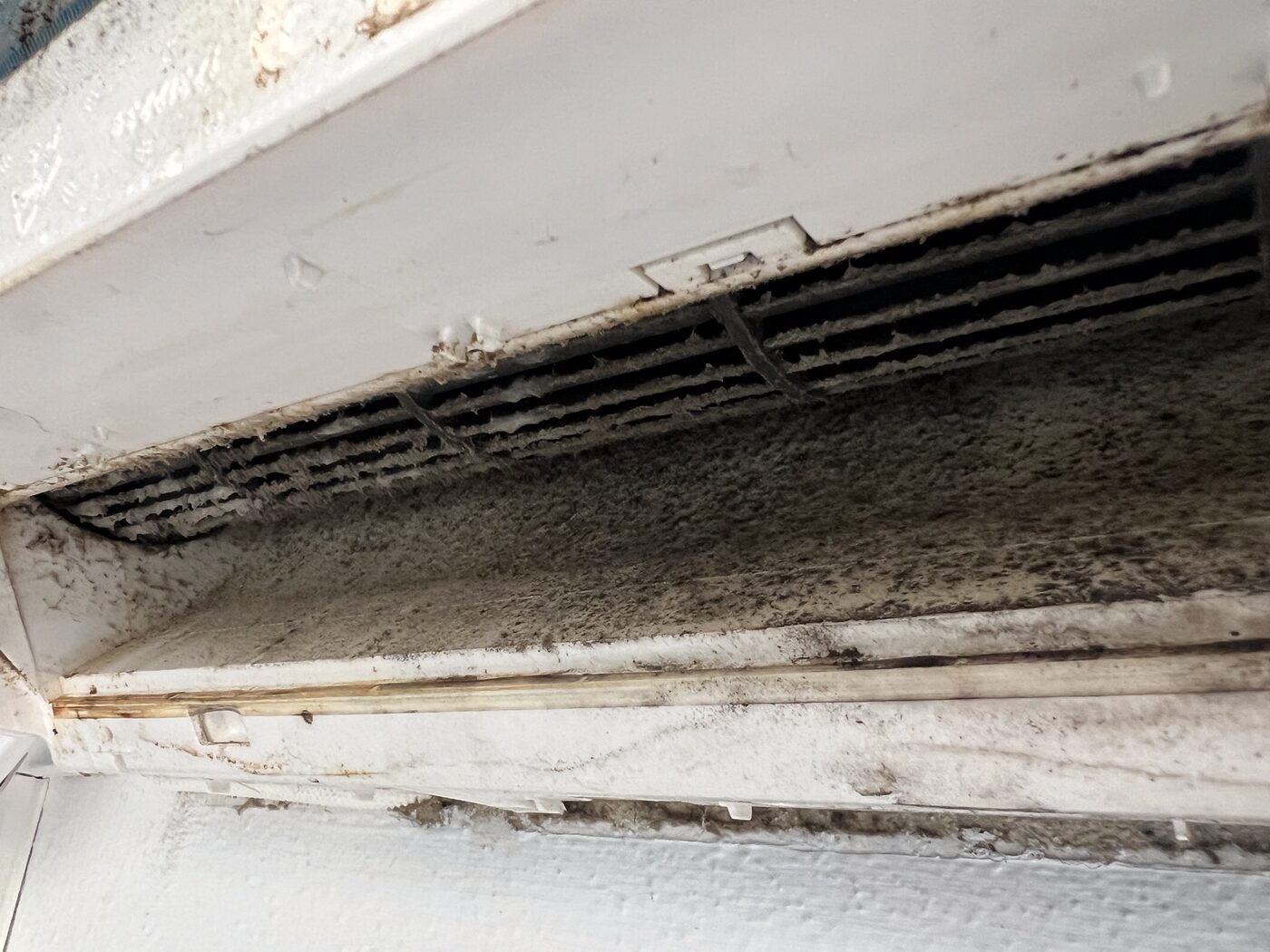 Dirty AC unit interior: discharge louvre and tray heavily fouled after a sustained high-use season in Ibiza.